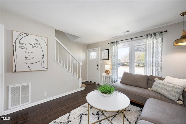 living area featuring baseboards, stairway, and wood finished floors