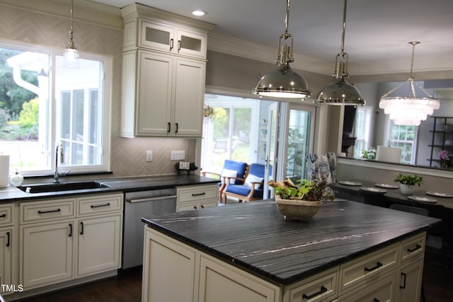 kitchen featuring a sink, dark countertops, stainless steel dishwasher, healthy amount of natural light, and ornamental molding