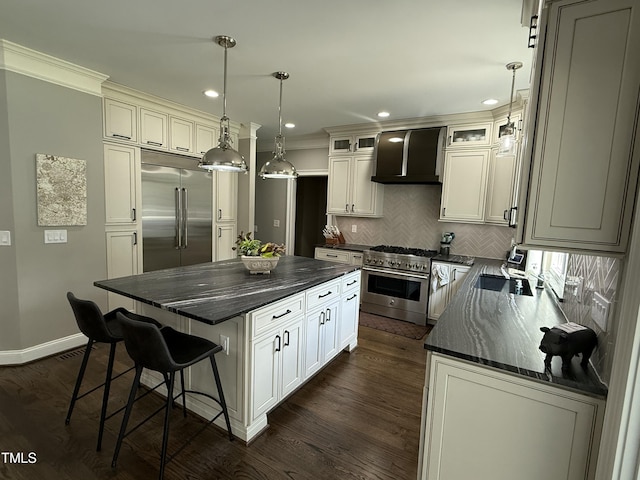 kitchen with high end appliances, wall chimney exhaust hood, ornamental molding, tasteful backsplash, and a center island