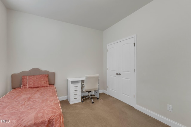 bedroom with carpet floors, baseboards, an office area, and a closet