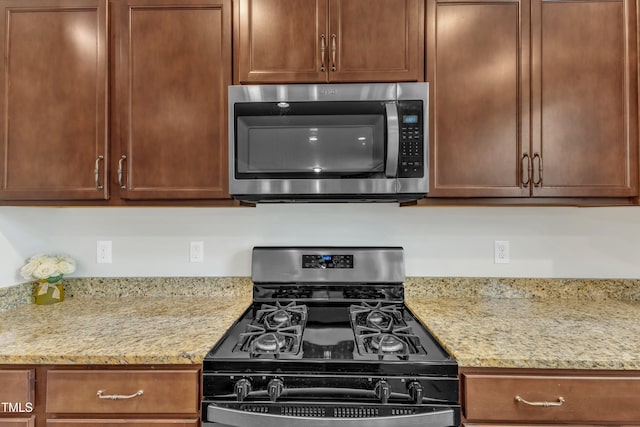 kitchen with stainless steel microwave, black gas stove, and light stone countertops