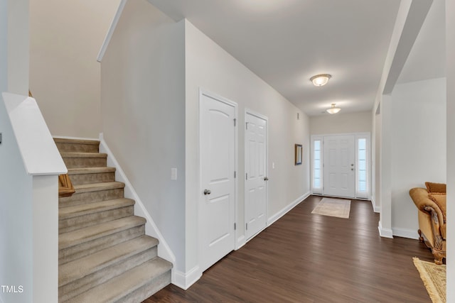 foyer entrance featuring dark wood-type flooring, stairs, and baseboards
