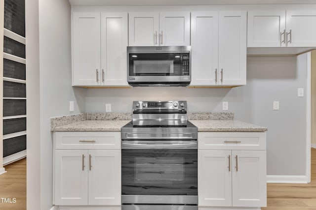 2600 Wade Ave, Raleigh, NC 27607 - kitchen featuring appliances with stainless steel finishes, light wood-style floors, white cabinets, and light stone counters