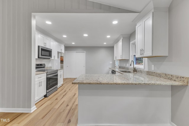 2600 Wade Ave, Raleigh, NC 27607 - kitchen with appliances with stainless steel finishes, a sink, light wood-style flooring, a peninsula, and white cabinets