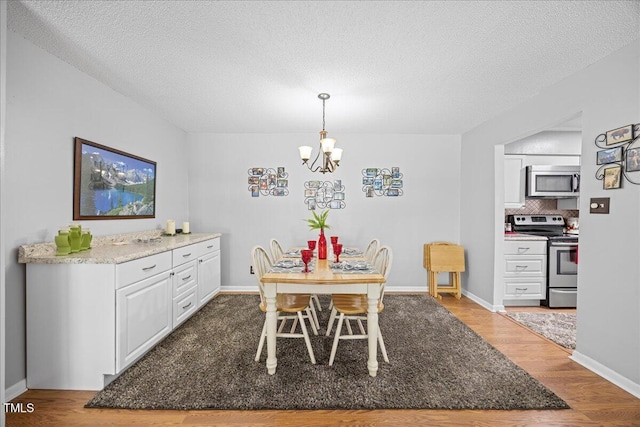 4709 Edwards Mill Rd Unit H, Raleigh, NC 27612 - dining room featuring wood finished floors, a chandelier, a textured ceiling, and baseboards