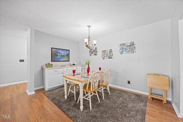 4709 Edwards Mill Rd Unit H, Raleigh, NC 27612 - dining space featuring light wood finished floors, a chandelier, a textured ceiling, and baseboards