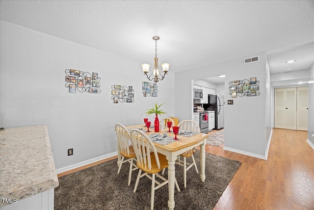 4709 Edwards Mill Rd Unit H, Raleigh, NC 27612 - dining room with light wood-style floors, a chandelier, a textured ceiling, and baseboards