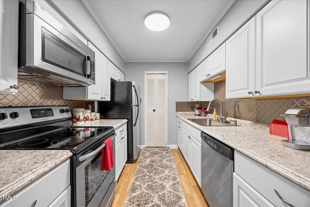 4709 Edwards Mill Rd Unit H, Raleigh, NC 27612 - kitchen with stainless steel appliances, a sink, white cabinetry, light wood finished floors, and tasteful backsplash