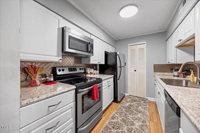 4709 Edwards Mill Rd Unit H, Raleigh, NC 27612 - kitchen with appliances with stainless steel finishes, a sink, ornamental molding, white cabinets, and light wood-style flooring