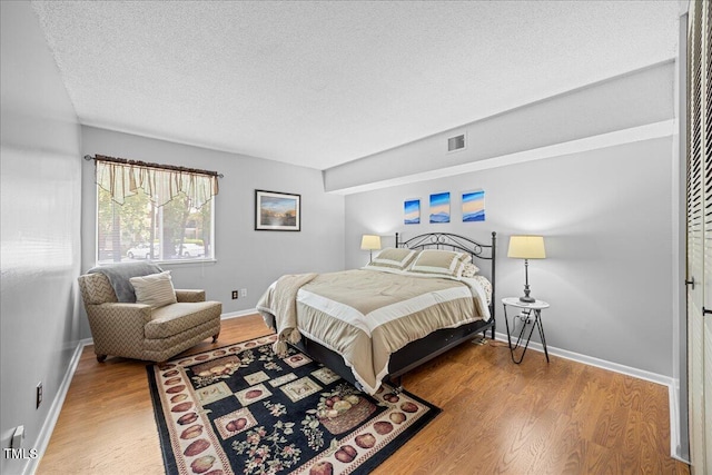 4709 Edwards Mill Rd Unit H, Raleigh, NC 27612 - bedroom with wood finished floors, a textured ceiling, and baseboards