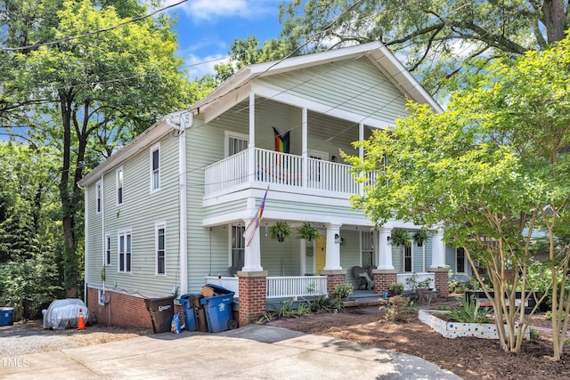 view of front of home featuring a balcony, a porch, and concrete driveway