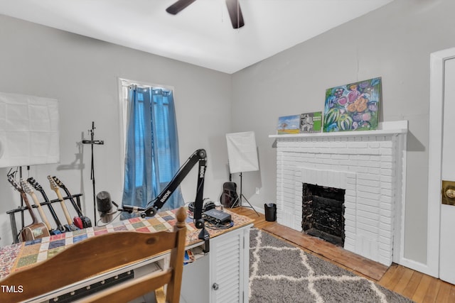 office space with ceiling fan, wood finished floors, and a brick fireplace