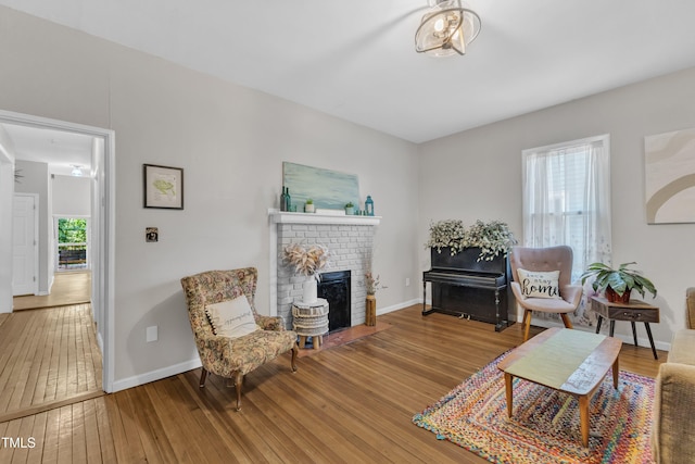 living area with hardwood / wood-style flooring, a brick fireplace, and baseboards