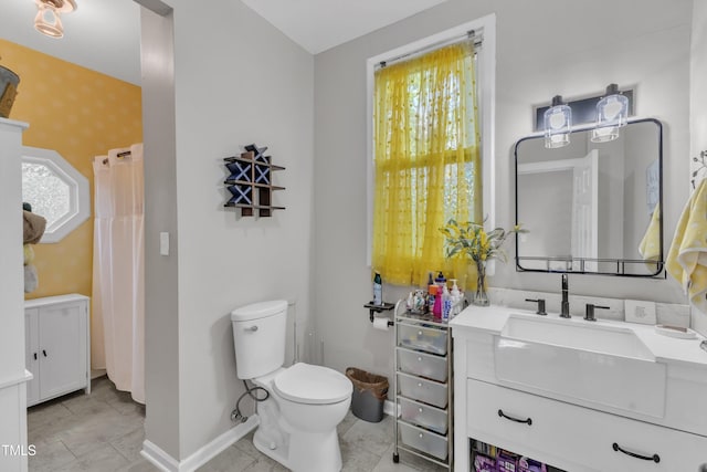 bathroom featuring toilet, baseboards, vanity, and wallpapered walls