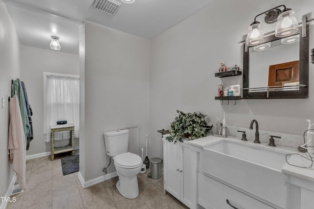 bathroom with toilet, vanity, and baseboards