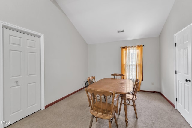 dining room with lofted ceiling, light colored carpet, and baseboards