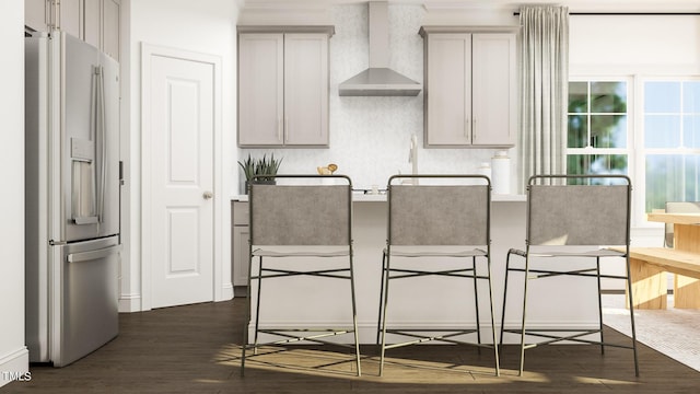 kitchen with fridge with ice dispenser, wall chimney range hood, a kitchen breakfast bar, dark wood finished floors, and gray cabinets