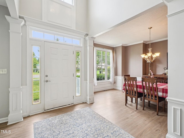 2317 Colony Woods Dr, Apex, NC 27523 - entryway with decorative columns, a chandelier, light wood-style flooring, ornamental molding, and a wainscoted wall