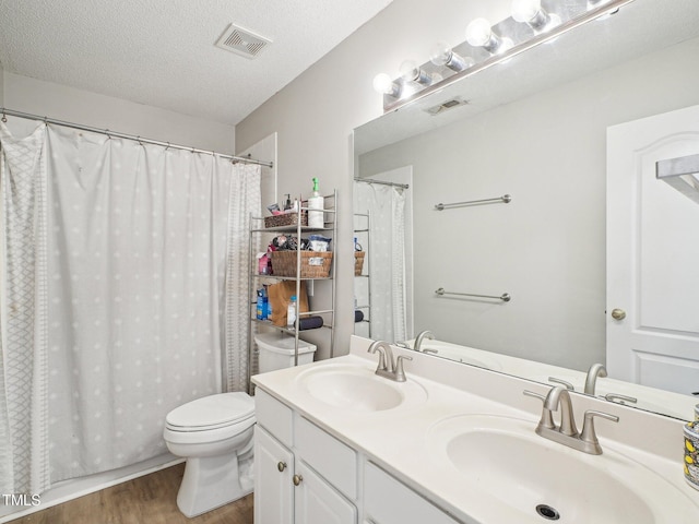 2317 Colony Woods Dr, Apex, NC 27523 - bathroom with wood finished floors, toilet, double vanity, a textured ceiling, and curtained shower