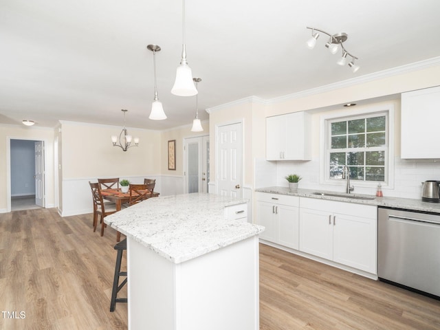 kitchen with dishwasher, a sink, a kitchen island, crown molding, and light stone counters