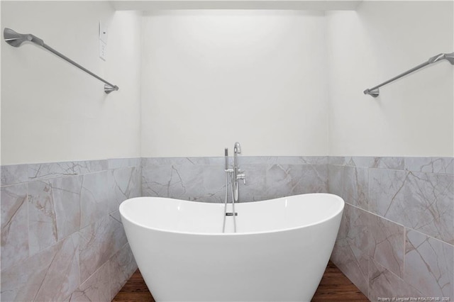 5704 Kindley Dr, Fayetteville, NC 28311 - bathroom featuring tile walls, a freestanding tub, a wainscoted wall, and wood finished floors