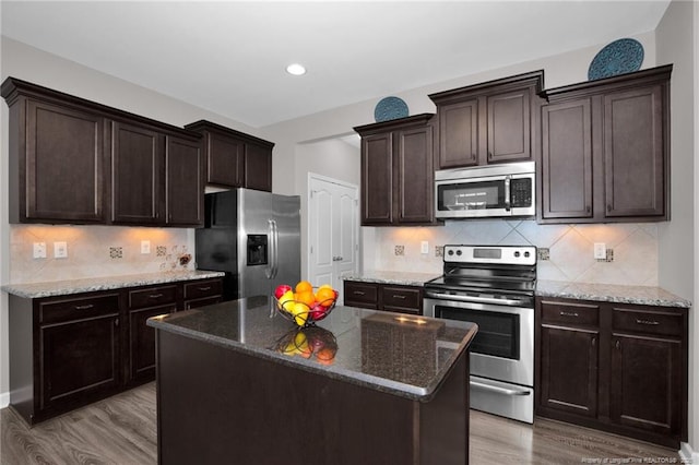 kitchen featuring stainless steel appliances, dark brown cabinetry, light wood finished floors, decorative backsplash, and recessed lighting