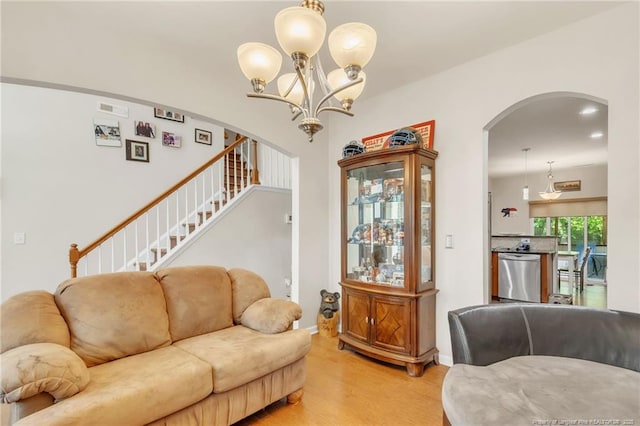 living area with arched walkways, light wood-style flooring, a chandelier, stairway, and baseboards