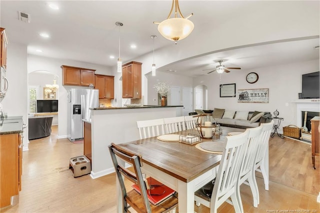 dining area with arched walkways, a ceiling fan, light wood-style flooring, and recessed lighting