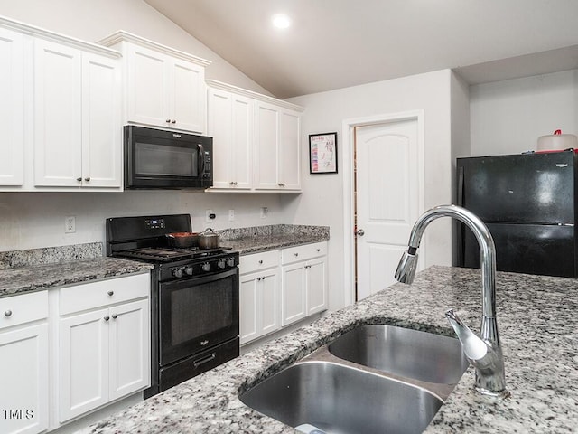kitchen with black appliances, a sink, vaulted ceiling, white cabinetry, and light stone counters