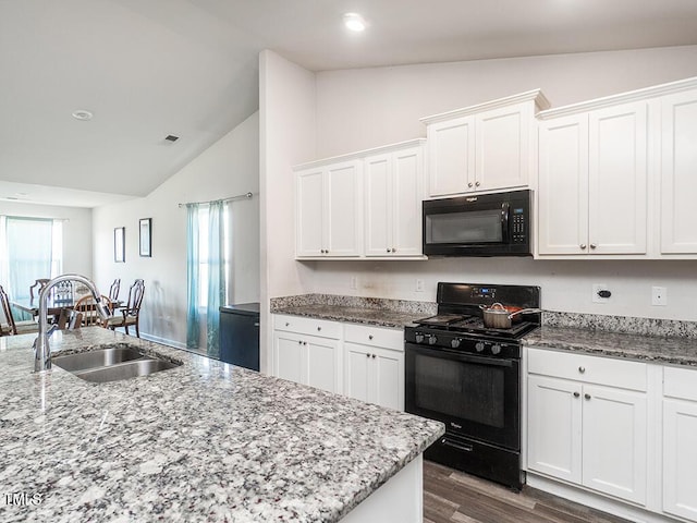 kitchen featuring black appliances, vaulted ceiling, a sink, white cabinets, and light stone countertops