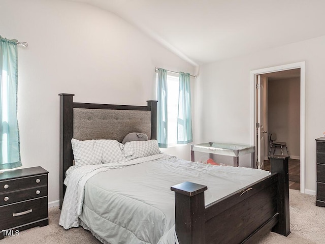 bedroom featuring lofted ceiling, light colored carpet, and baseboards