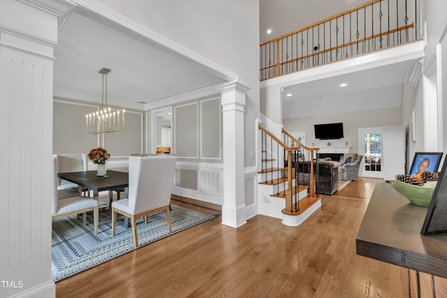 3007 Krogen Ct, Creedmoor, NC 27522 - dining space with a fireplace, wood finished floors, stairs, a towering ceiling, and a chandelier