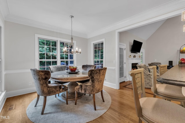 3007 Krogen Ct, Creedmoor, NC 27522 - dining space featuring a chandelier, light wood finished floors, a lit fireplace, crown molding, and baseboards