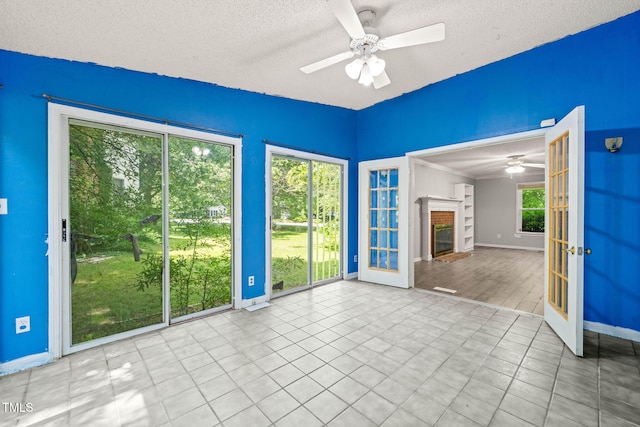 3 Cobble Glen Ct, Durham, NC 27713 - tiled empty room with ceiling fan, baseboards, a textured ceiling, french doors, and a glass covered fireplace