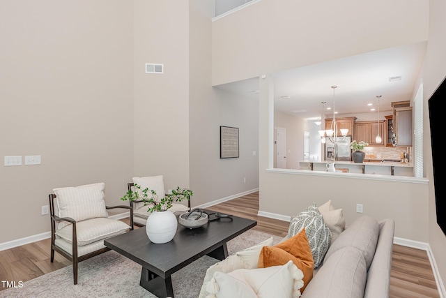 living area with light wood-type flooring, a chandelier, baseboards, and recessed lighting
