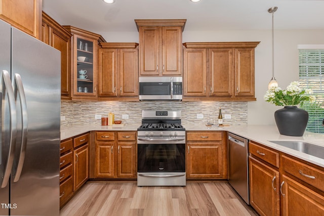 kitchen with stainless steel appliances, brown cabinetry, light wood-style flooring, light countertops, and recessed lighting