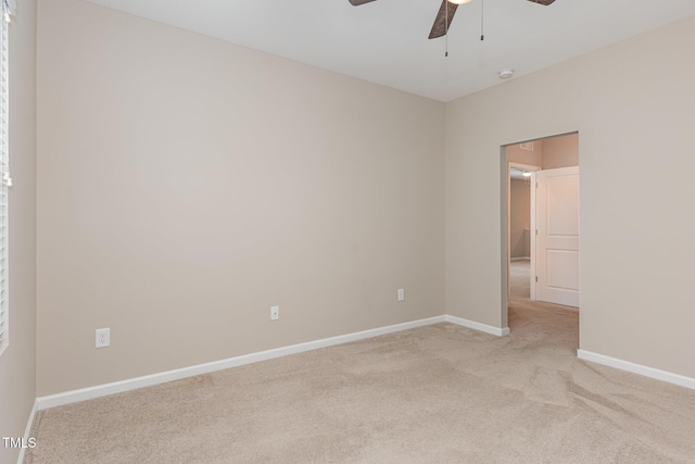 spare room with ceiling fan, light colored carpet, and baseboards