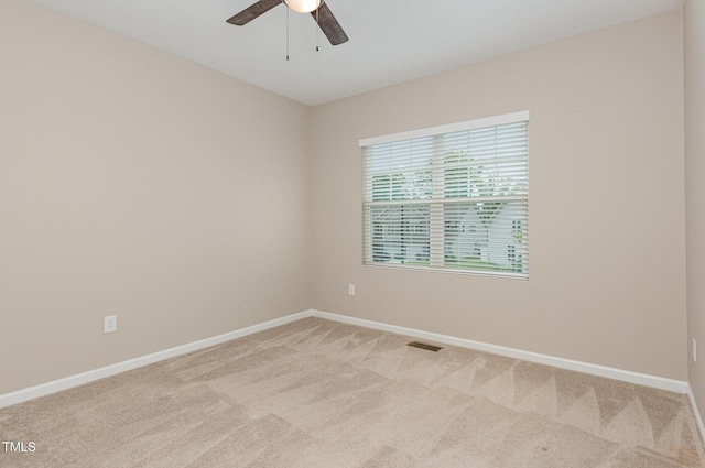 spare room featuring light colored carpet, baseboards, and ceiling fan