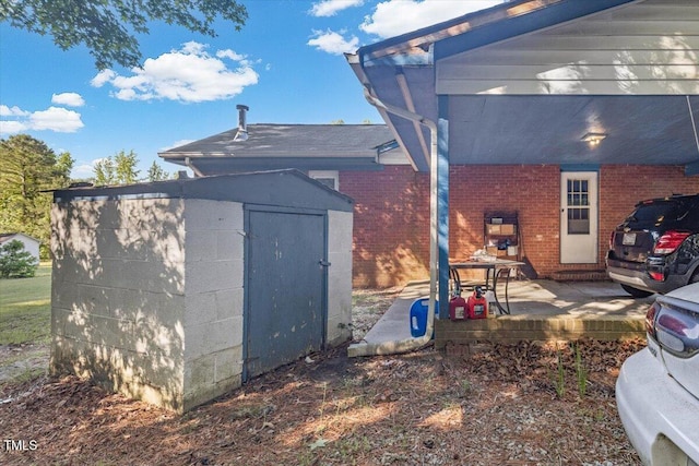 view of side of property featuring a shed, brick siding, an outdoor structure, and a patio