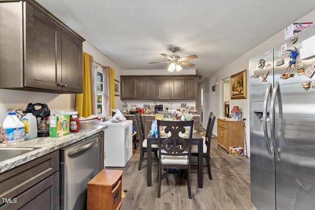 kitchen featuring stainless steel appliances, wood finished floors, ceiling fan, dark brown cabinetry, and a textured ceiling