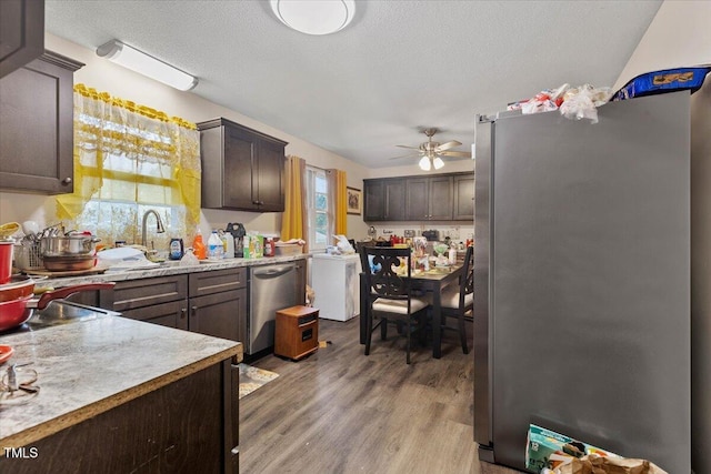 kitchen with appliances with stainless steel finishes, a sink, a ceiling fan, light countertops, and wood finished floors