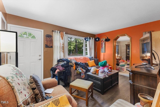 living area featuring arched walkways and wood finished floors