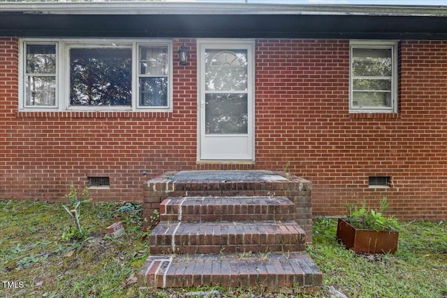 property entrance featuring crawl space and brick siding