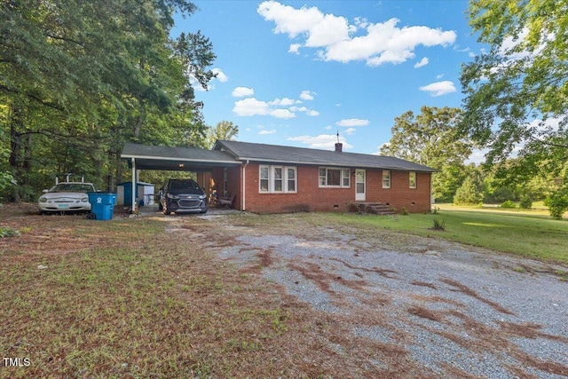 view of front facade featuring a carport, dirt driveway, a front lawn, brick siding, and crawl space
