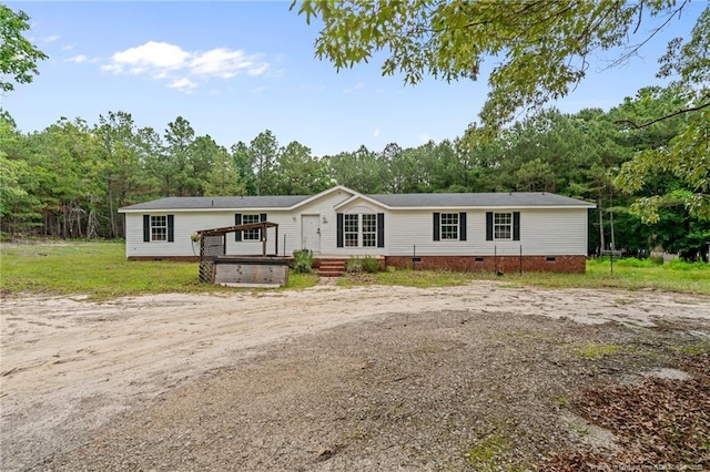 manufactured / mobile home with crawl space, a wooden deck, and view of scattered trees
