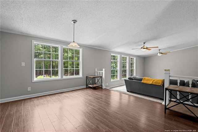 living area with a textured ceiling, crown molding, ceiling fan, wood finished floors, and baseboards