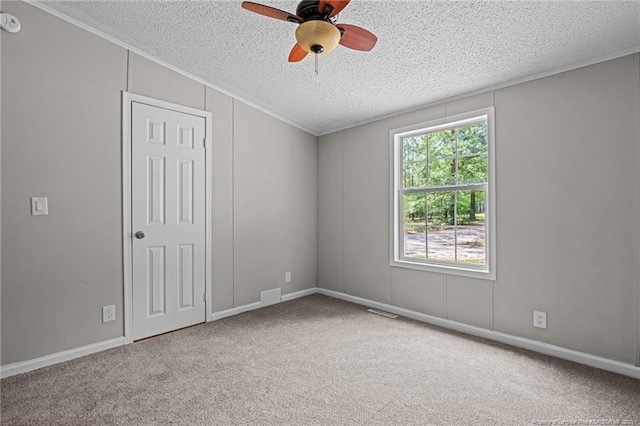 unfurnished room featuring a textured ceiling, a ceiling fan, carpet floors, and ornamental molding