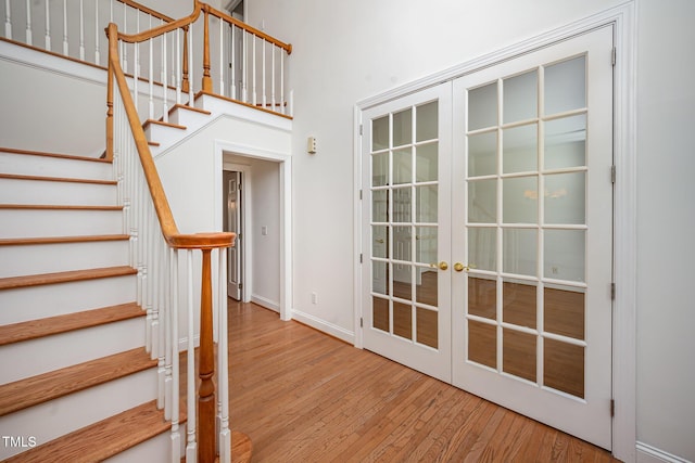 stairway featuring french doors, hardwood / wood-style flooring, and baseboards