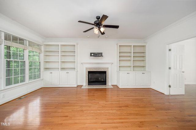 unfurnished living room with ornamental molding, light wood-style flooring, a ceiling fan, a premium fireplace, and baseboards