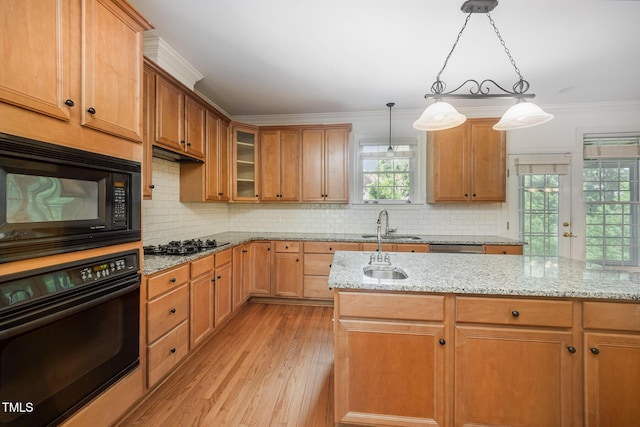 kitchen featuring black appliances, light wood-style flooring, light stone countertops, tasteful backsplash, and ornamental molding
